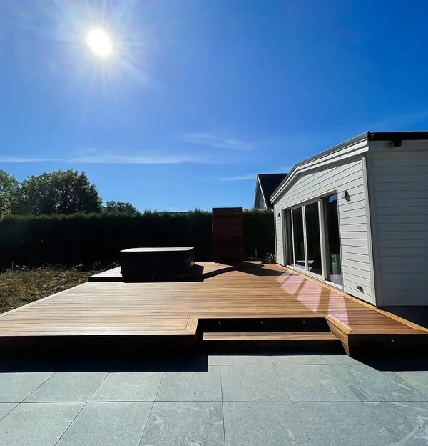 Nybyggt trädäck med trappsteg vid ett vitt hus